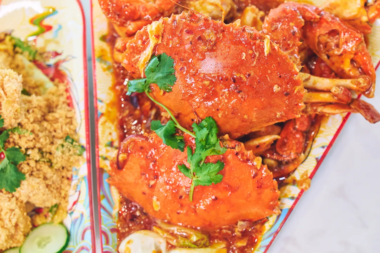 Chilli crab garnished with coriander, served next to cereal prawns