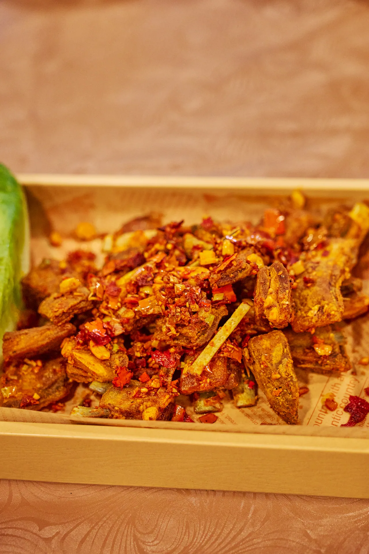 Crispy fried chicken coated in chilli and garlic in a wooden tray
