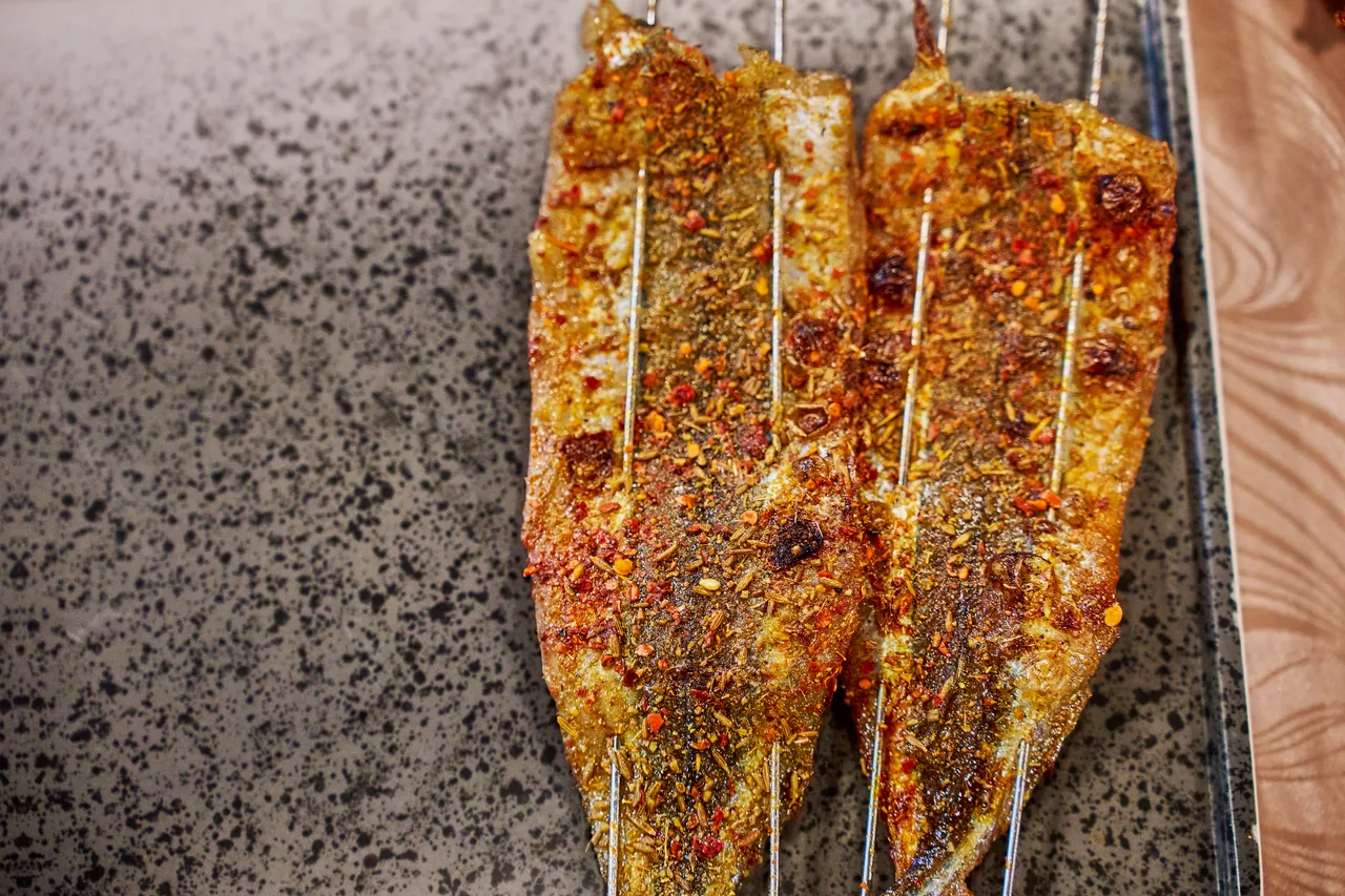 Grilled fish skewers with chilli spice on a stone slab