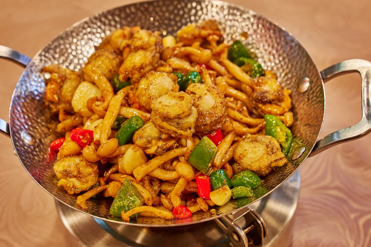 Stir-fried mushrooms with green and red peppers in a steel dry pot
