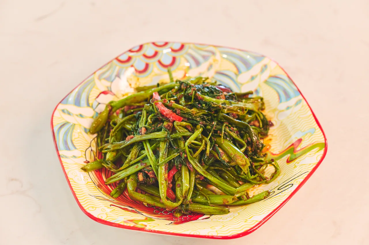 Stir-fried kangkong with chilli on a patterned plate