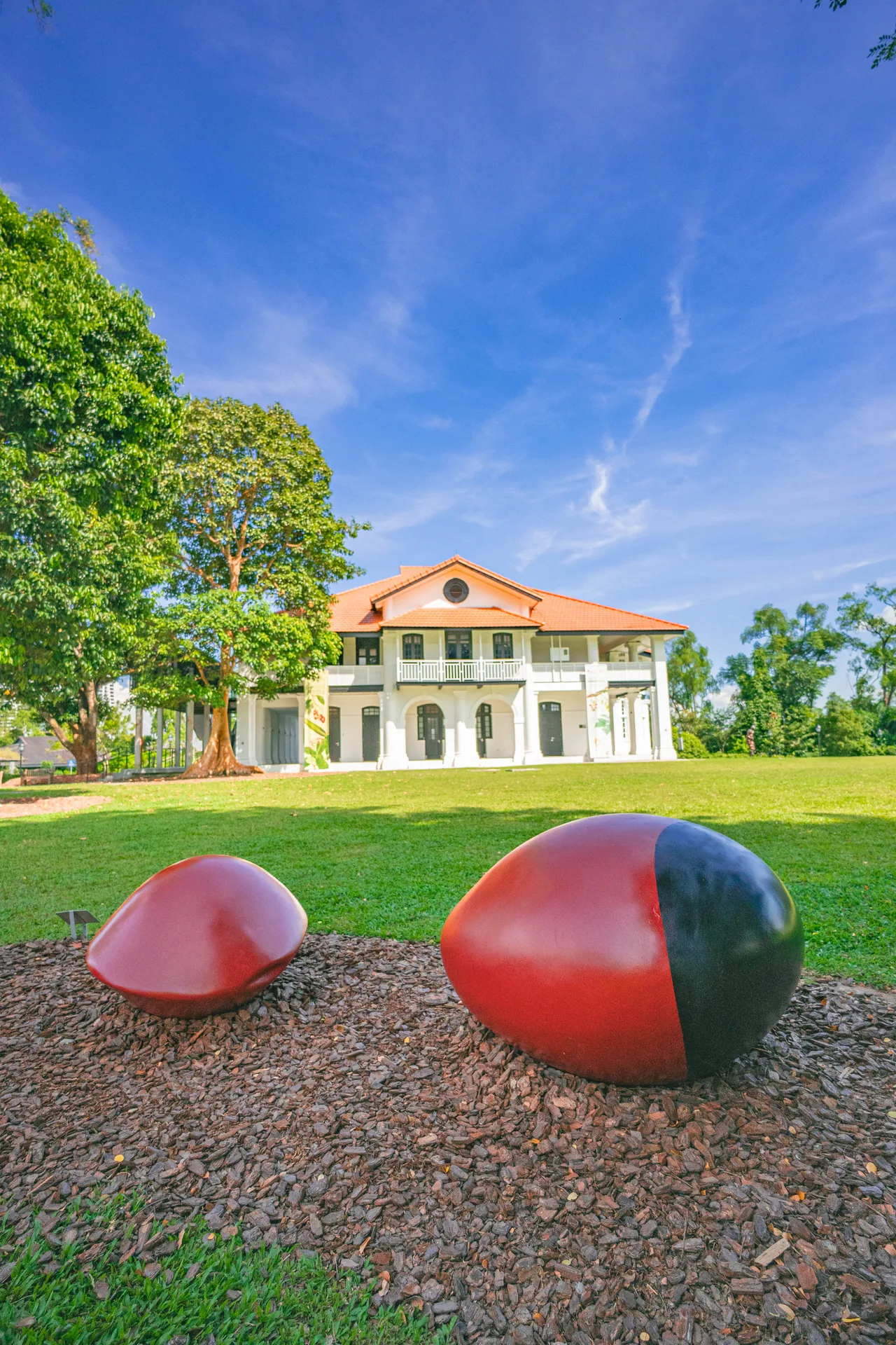 White colonial house on a lawn with red sculptures in front
