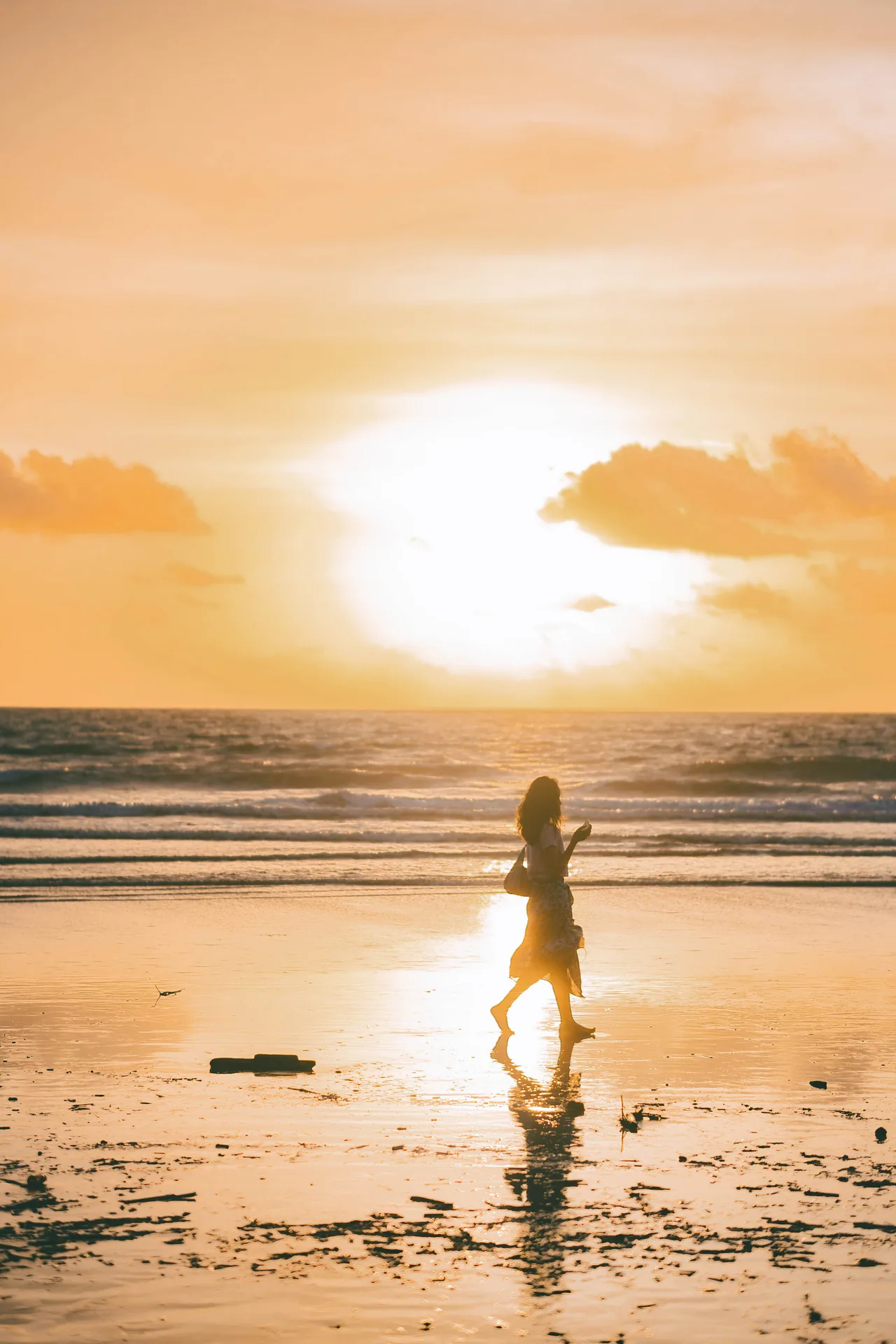 Person walking on a beach at golden sunset