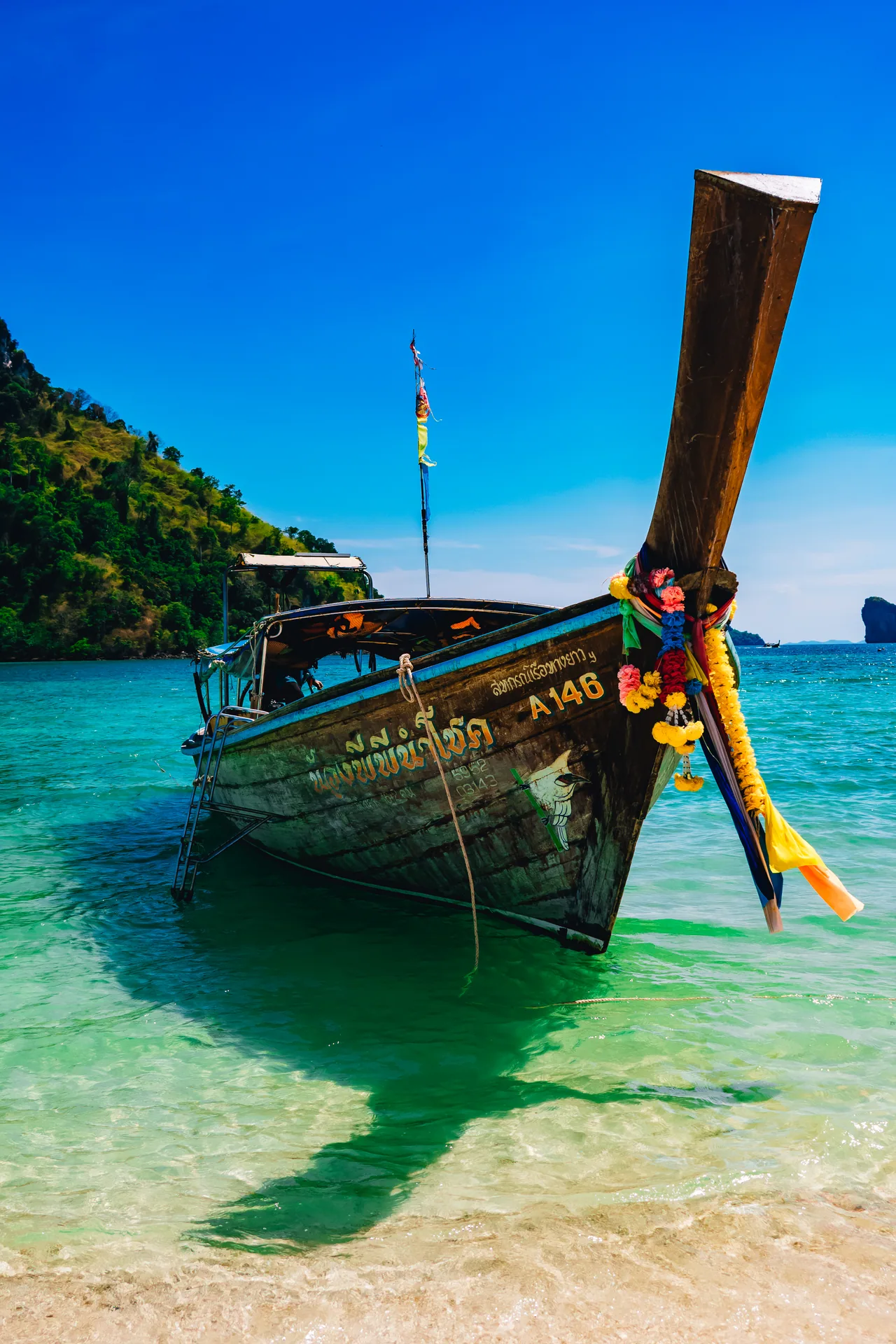 Longtail boat anchored in clear shallow water off a beach