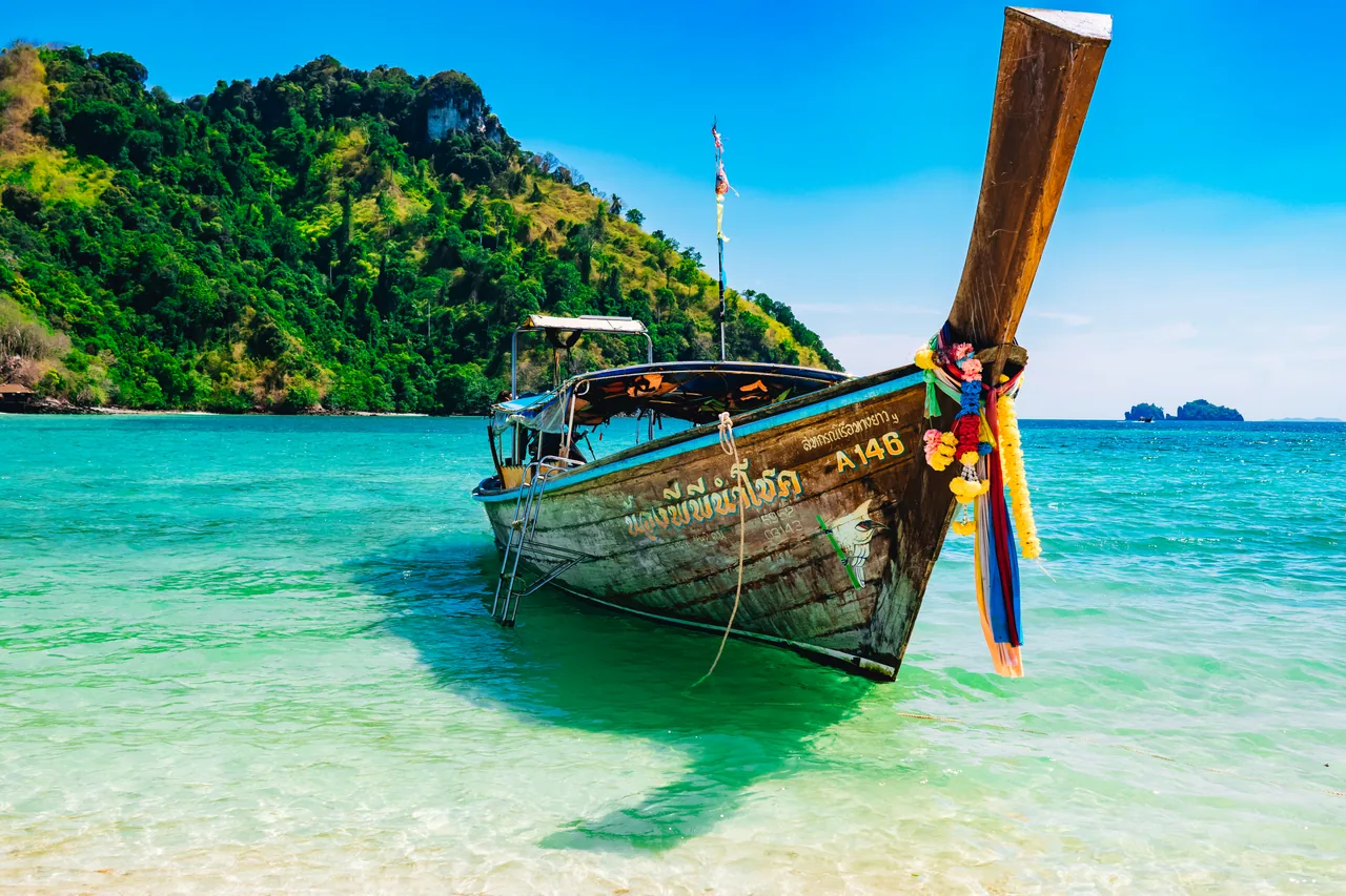 Longtail boat on turquoise water beside a green island