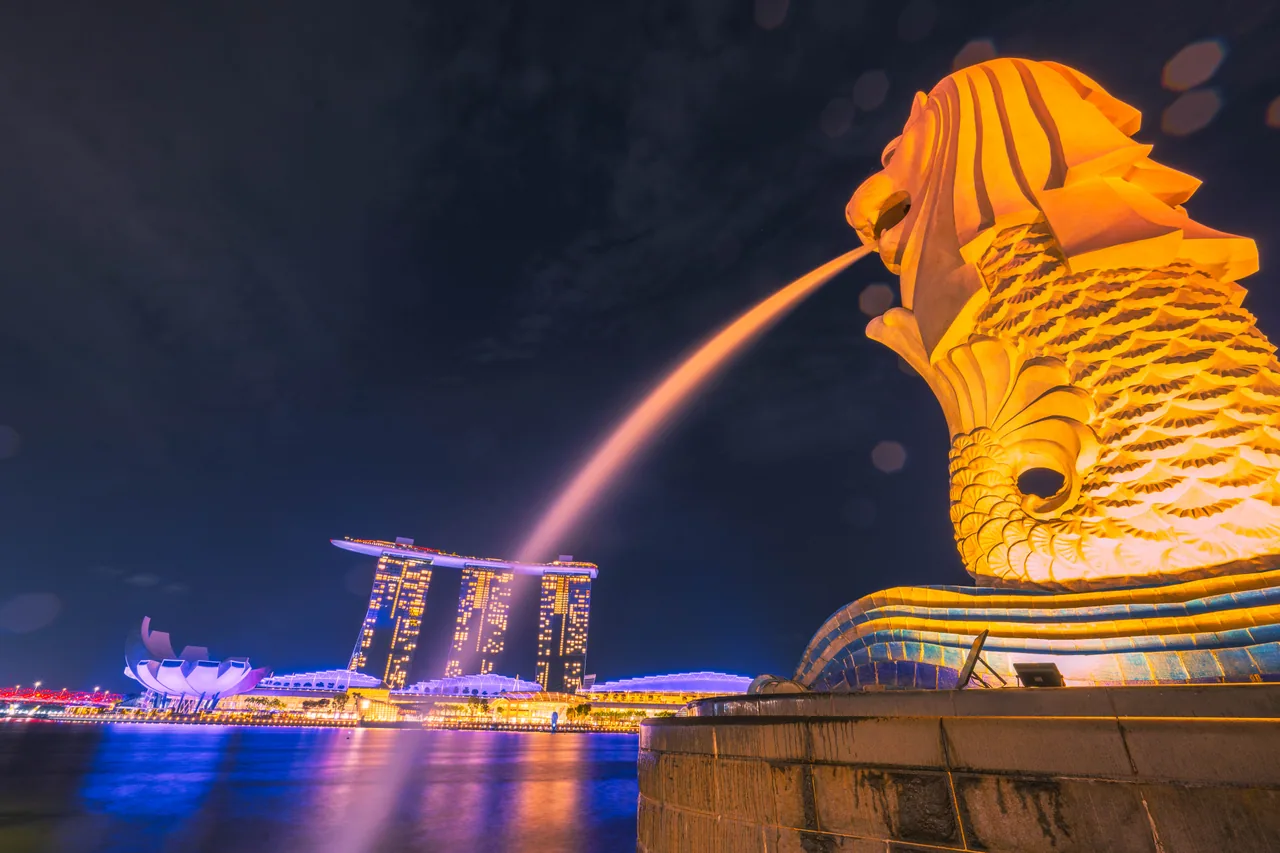 Merlion lit up at night with Marina Bay Sands behind