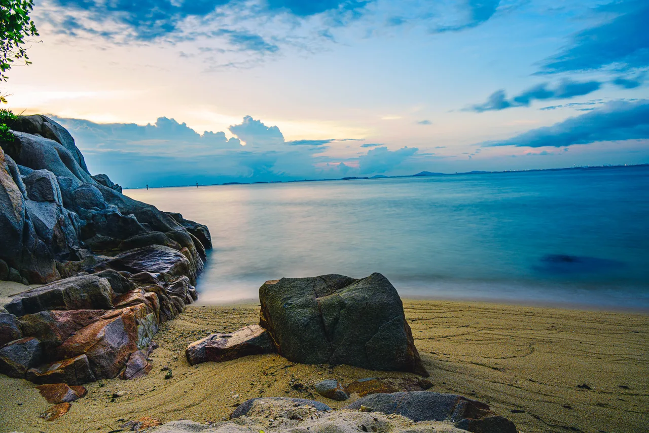 Rocky beach at blue hour with soft clouds over the water