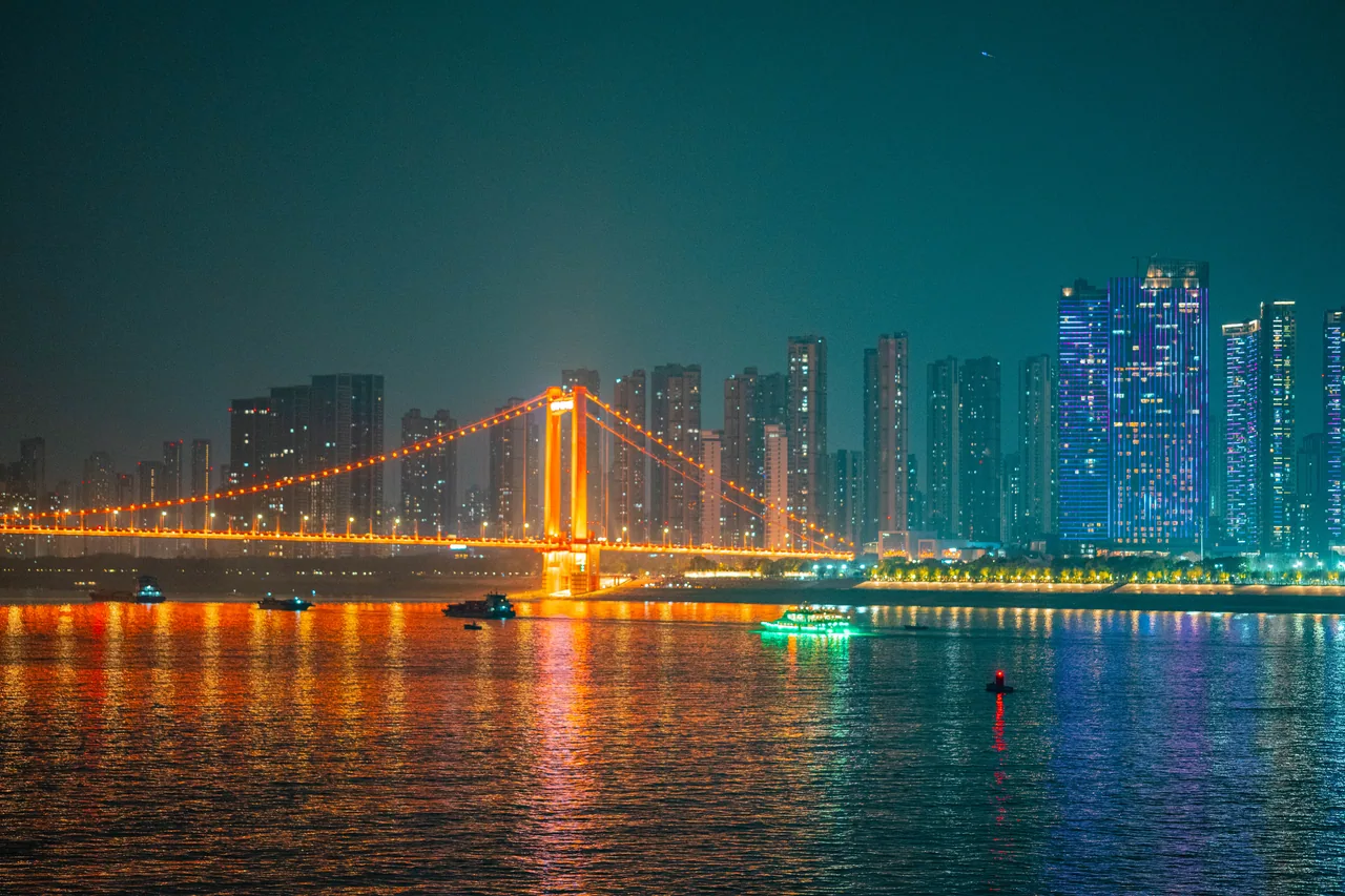 Suspension bridge and city lights reflected in a river at night