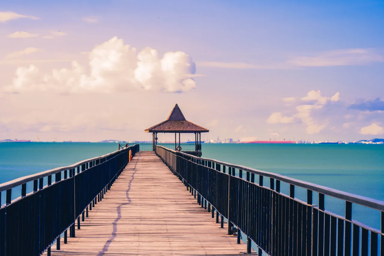 Long wooden jetty leading to a gazebo over a calm sea