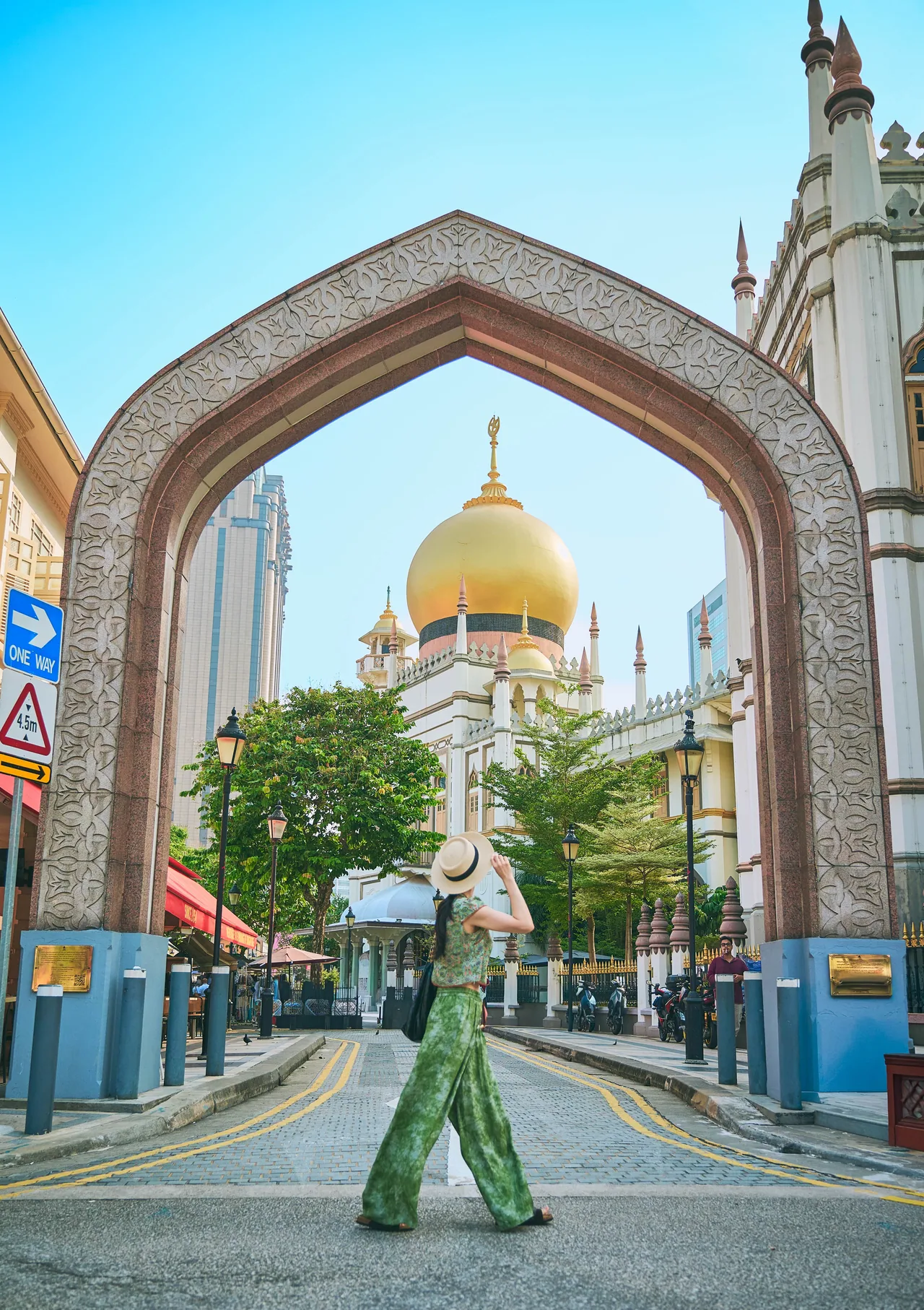 Woman walking under an archway with Sultan Mosque behind, Kampong Glam