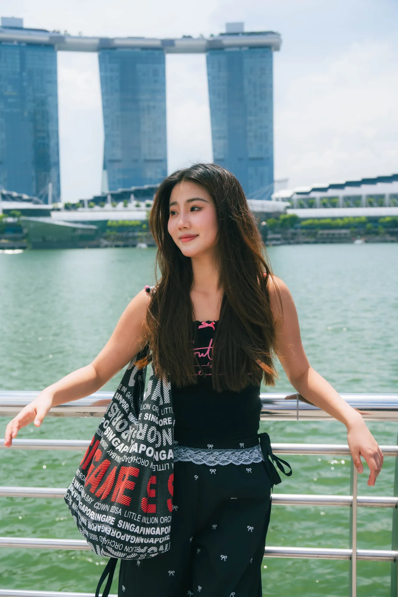Woman leaning on the railing with Marina Bay Sands across the water