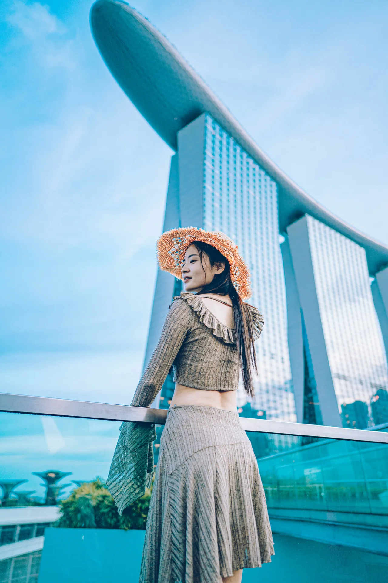 Woman in a sun hat on a bridge beside Marina Bay Sands