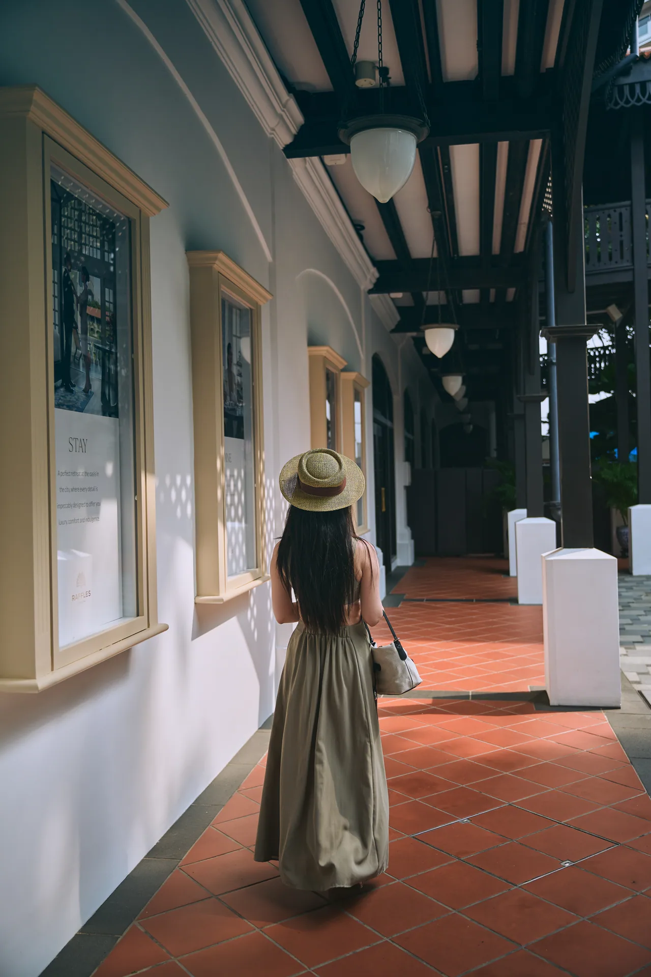 Woman walking along a colonial veranda at Raffles Hotel