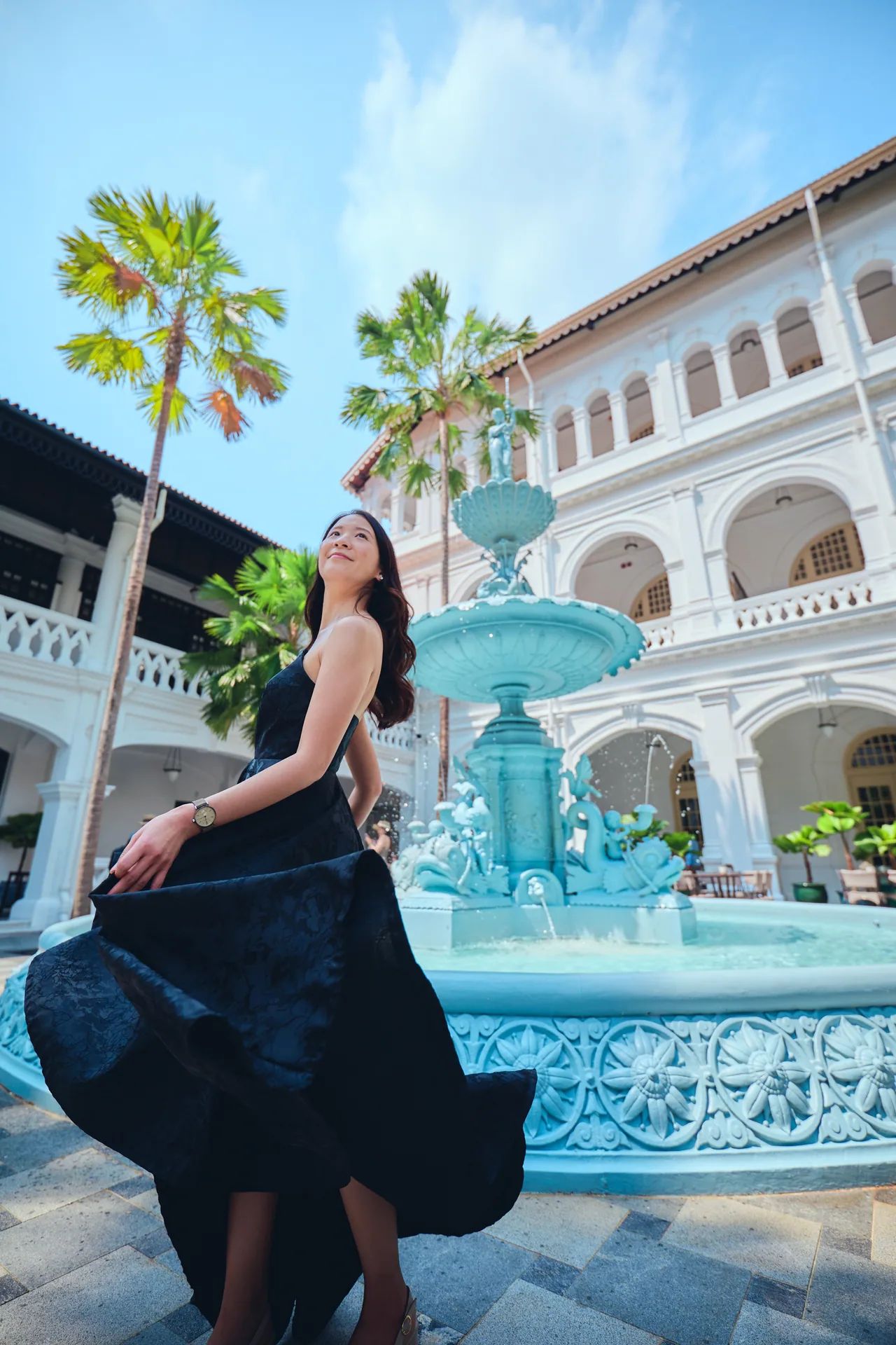 Twirling navy dress in front of the Raffles Hotel fountain