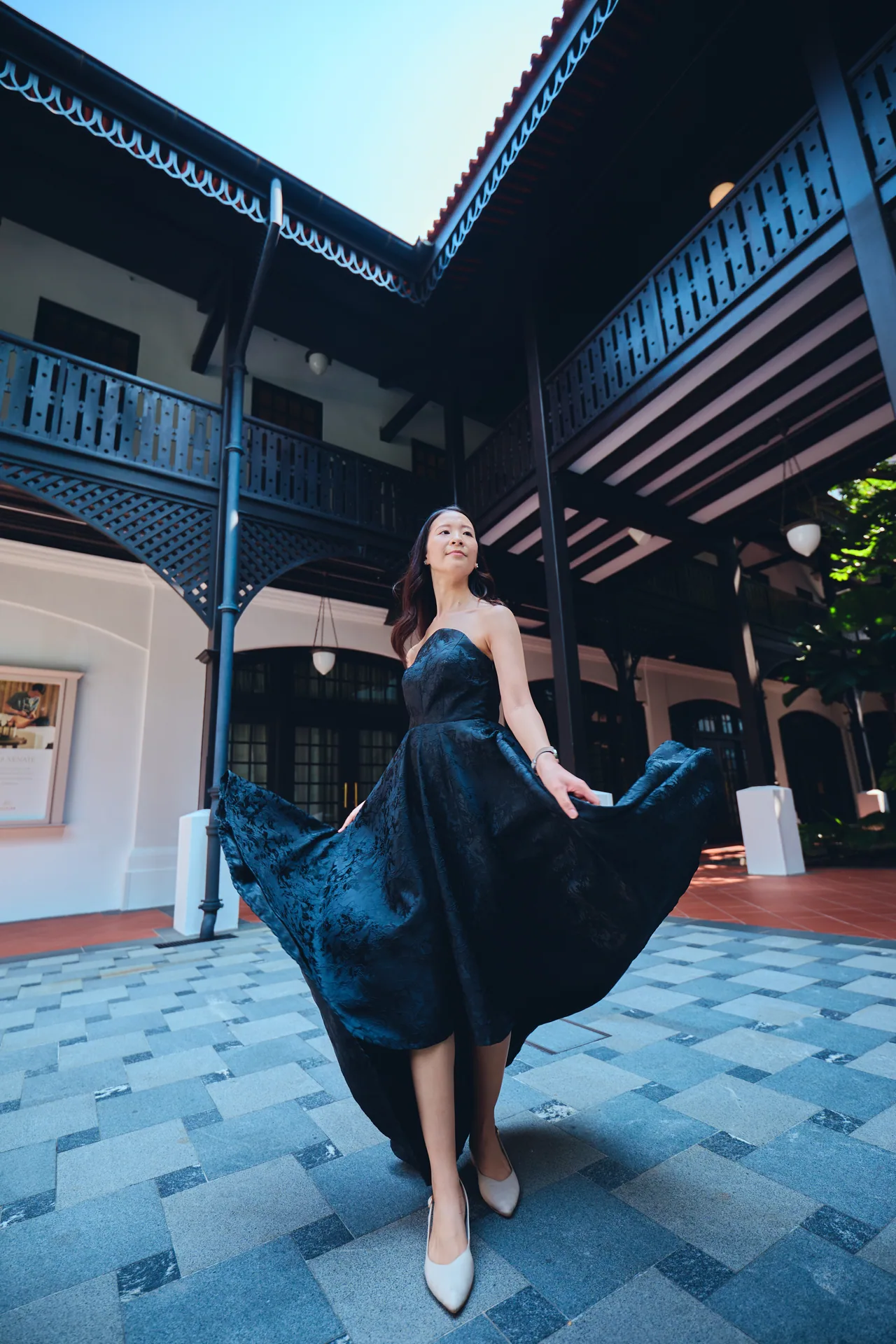 Woman in a flowing navy dress in a Raffles Hotel courtyard