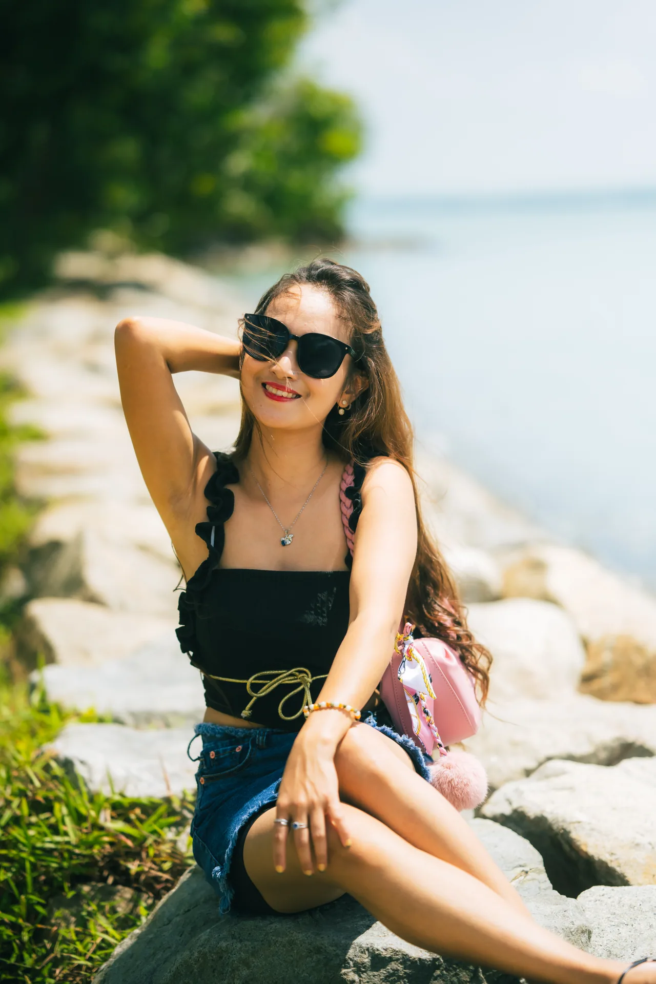 Woman in sunglasses sitting on seaside rocks