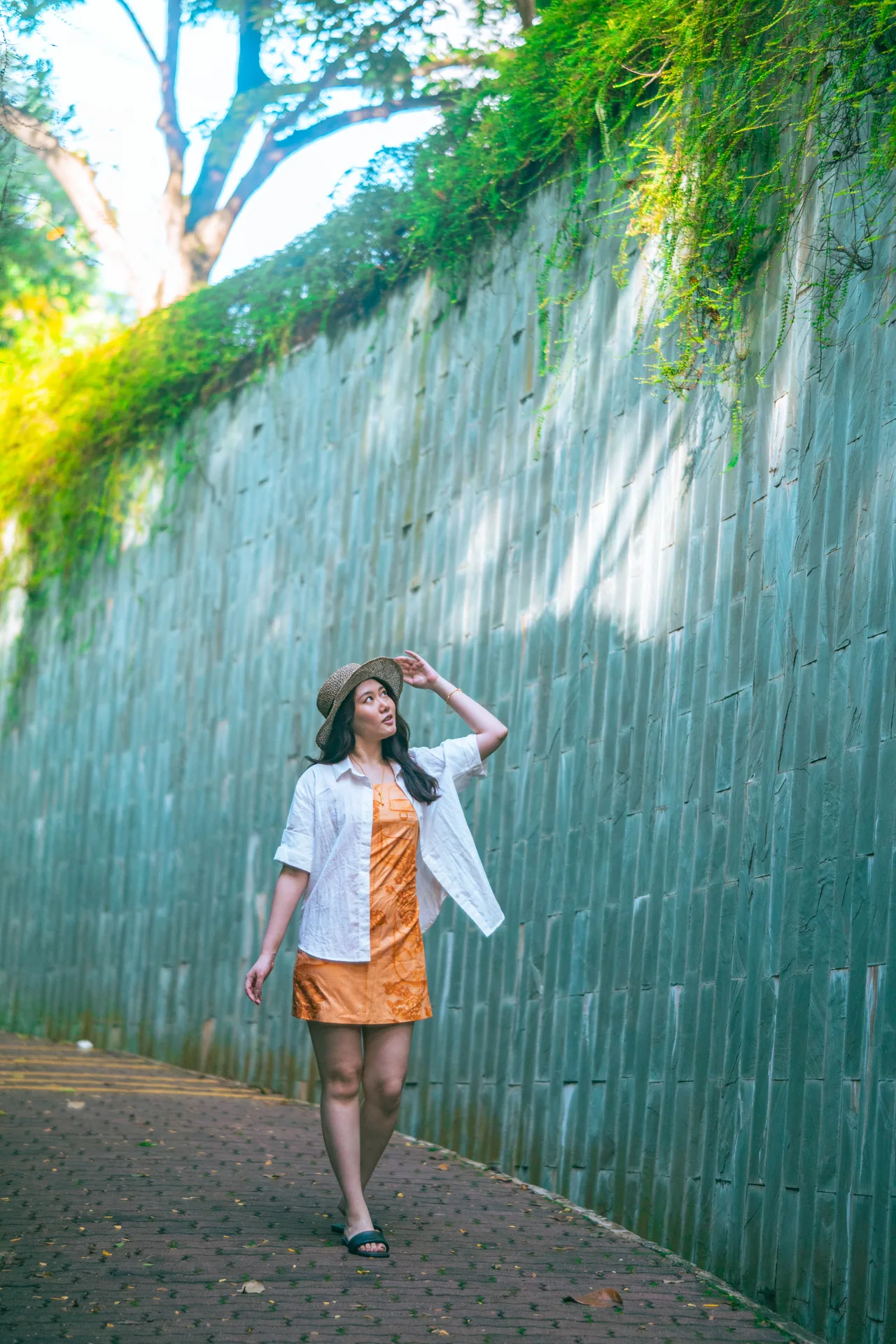 Woman walking past a wall of green leaves