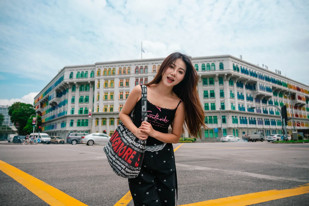 Woman posing on a street corner in front of a colourful heritage building