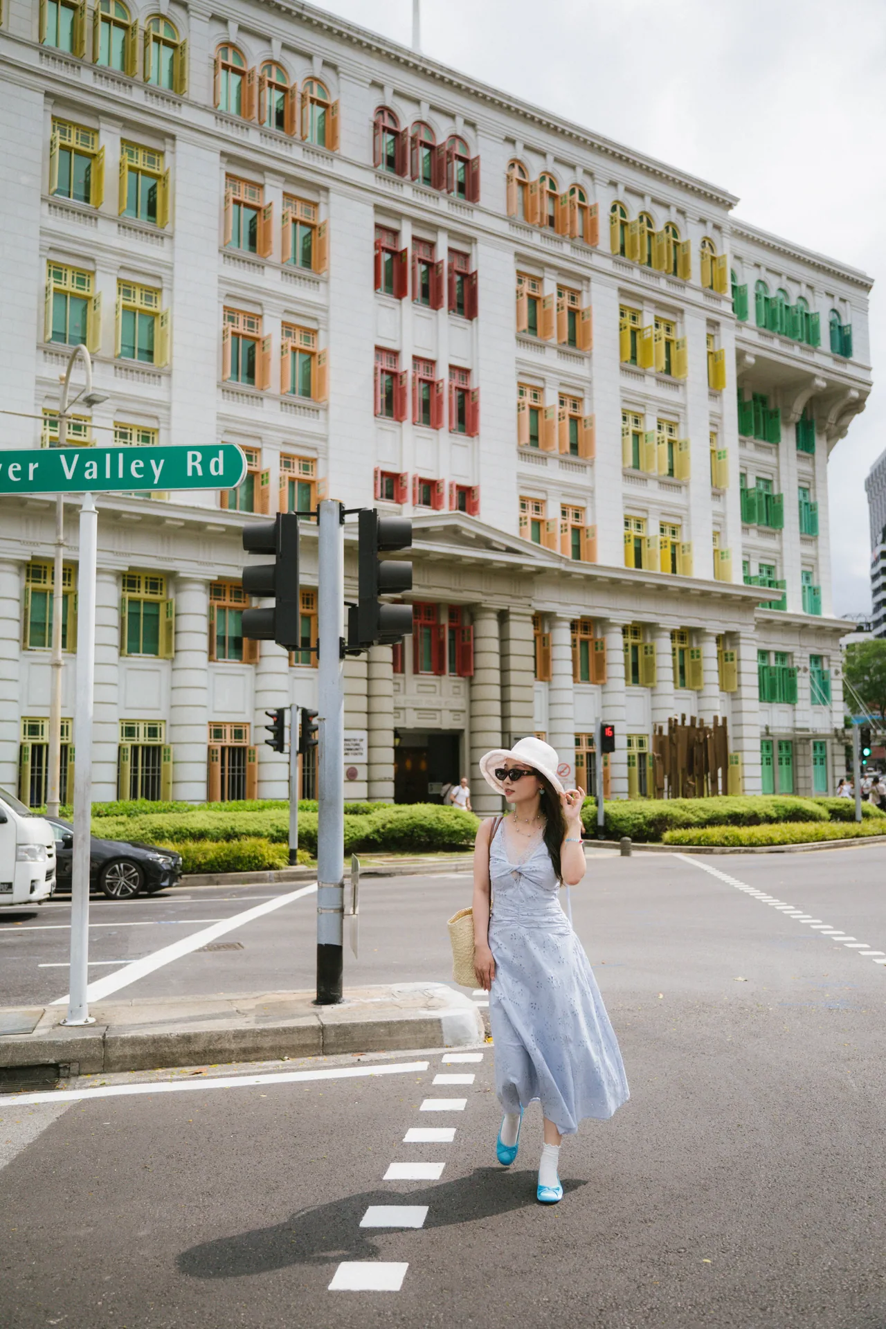 Woman in a blue dress crossing the street by a colourful colonial building
