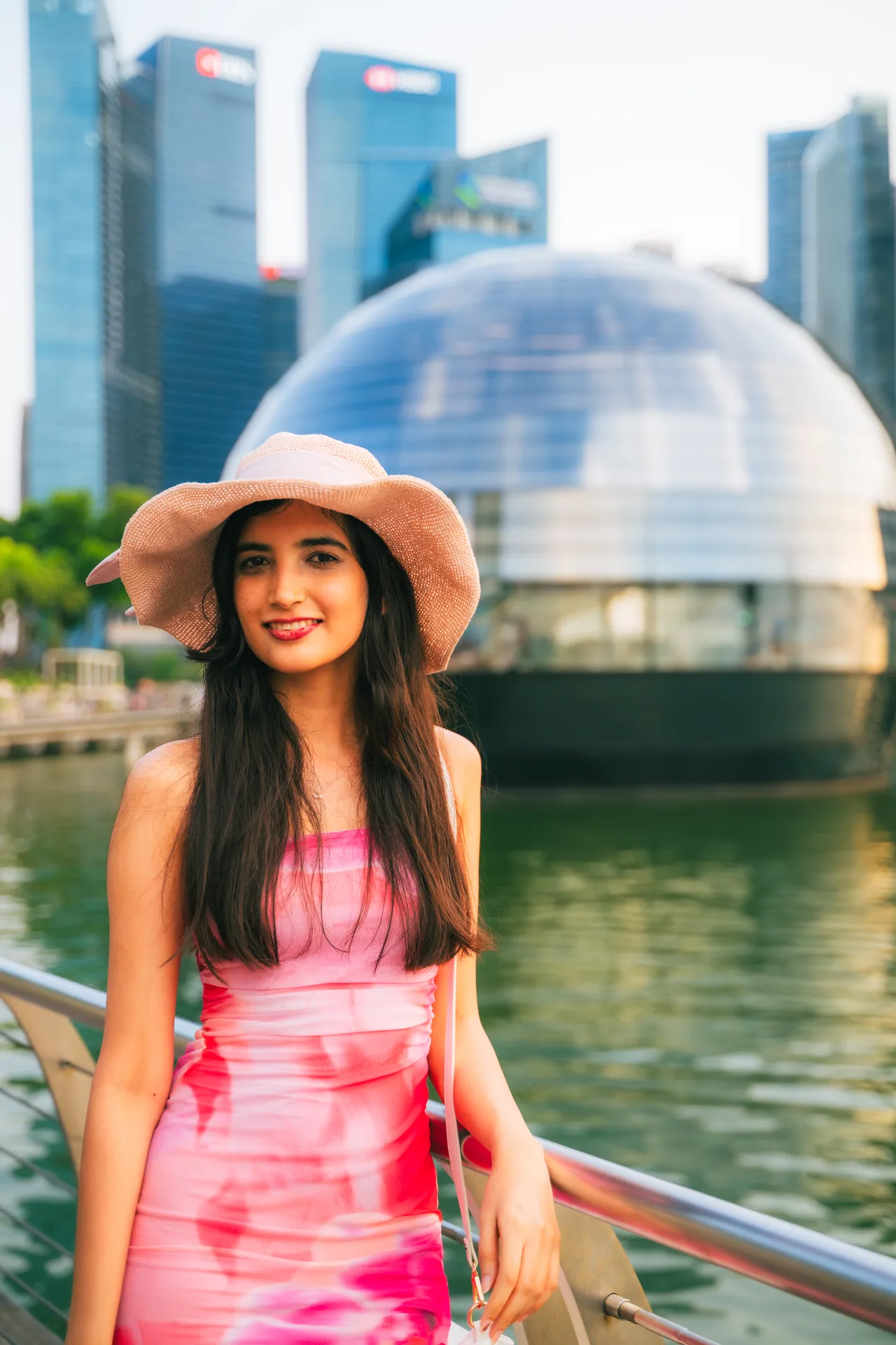 Woman in a pink dress and straw hat on the Marina Bay waterfront
