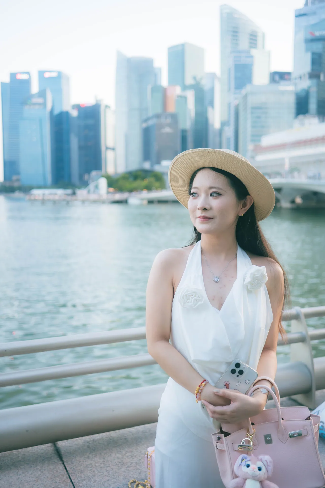 Woman in a white dress and straw hat with the Marina Bay skyline