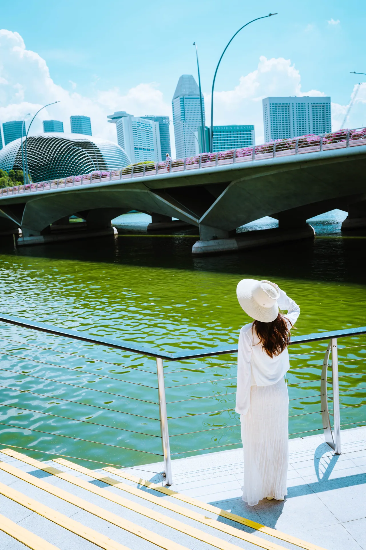Woman in white on the waterfront steps looking toward the Esplanade bridge